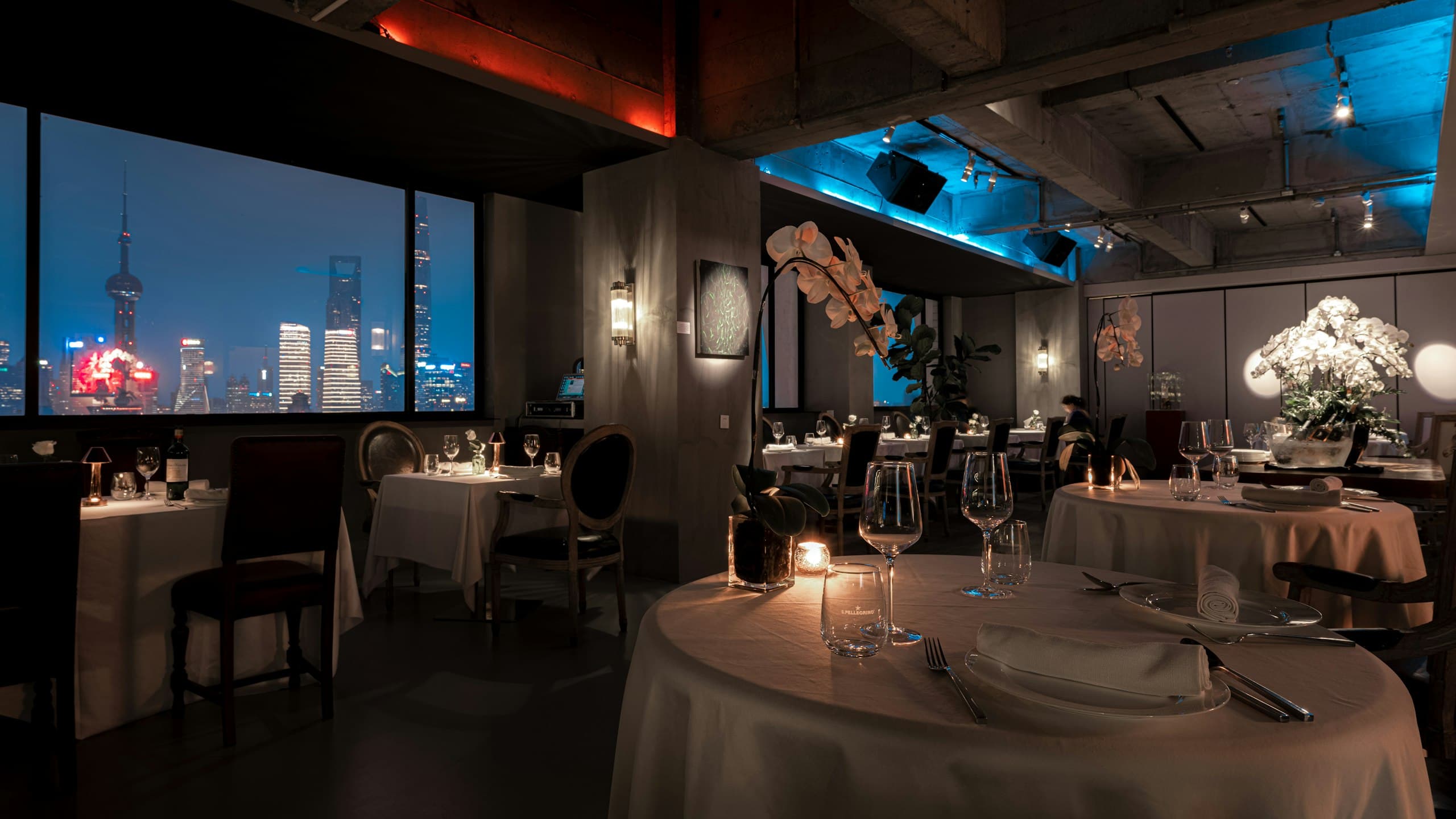 Candle-lit fine dining room overlooking a city skyline