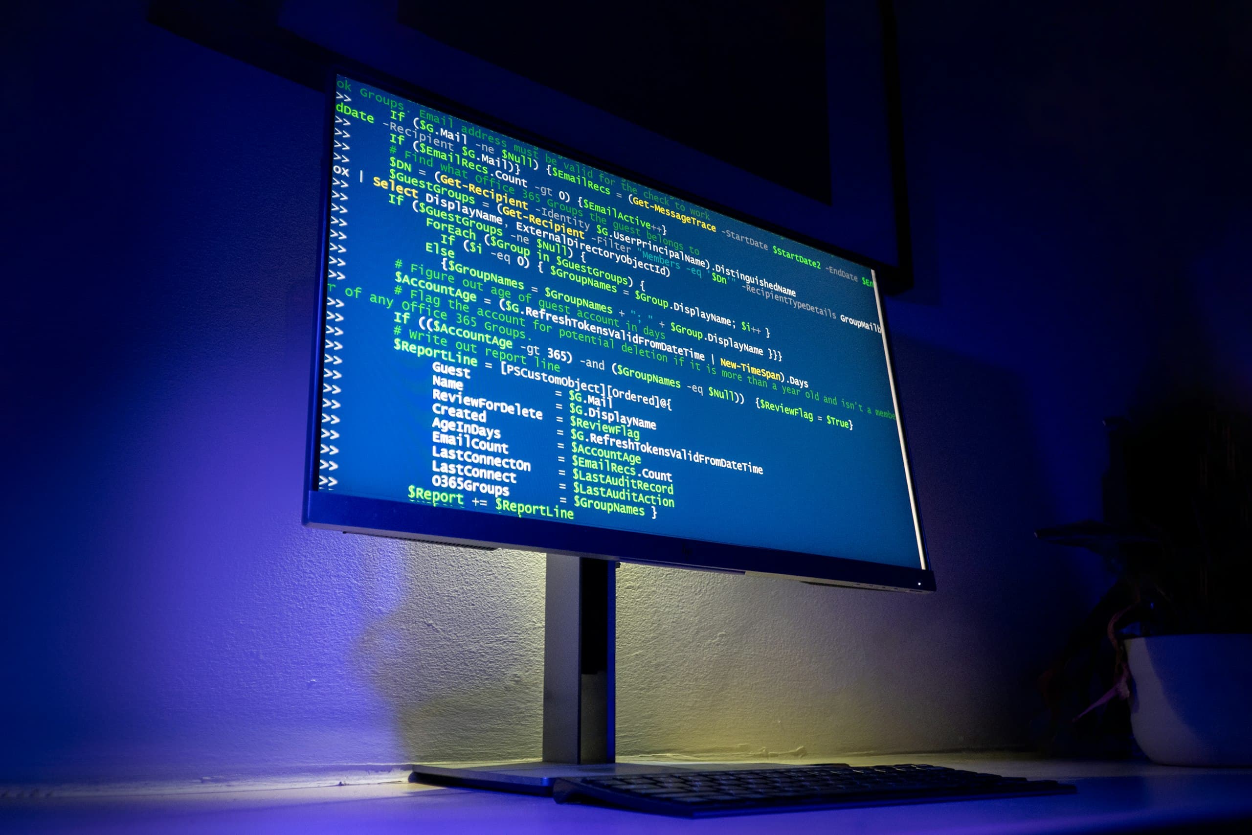 Monitor displaying code in a blue-lit room